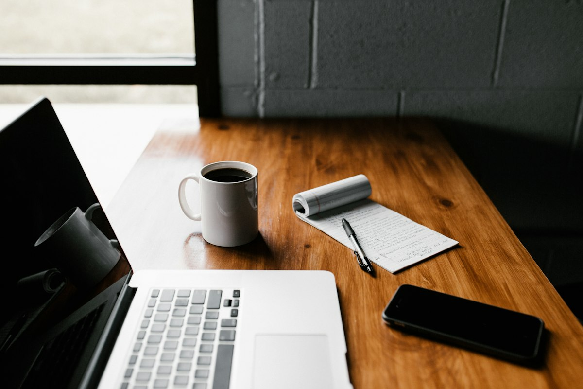 Laptop, notebook, and coffee on a wooden desk